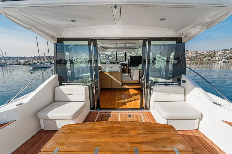 Slide: The Image of 2021 Tiara Yachts 53 Coupe interior with elegant seating and wooden table, overlooking marina. - 36