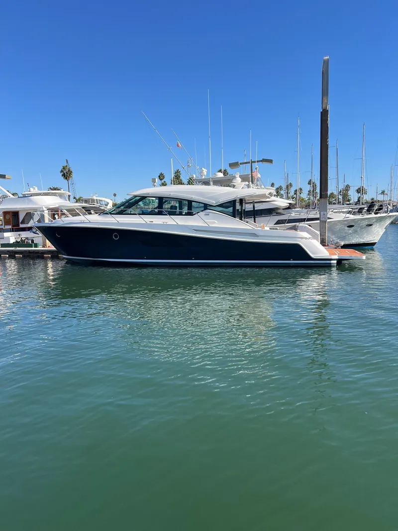Slide: The Image of 2021 Tiara Yachts 53 Coupe docked in a marina under clear blue skies. - 5