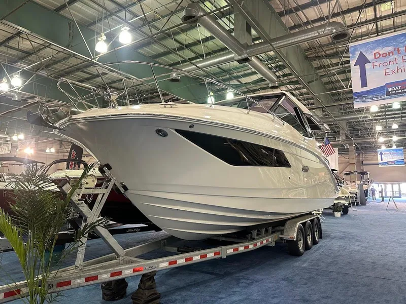 Slide: The Image of 2025 Sea Ray Sundancer 320 on display at a boat show indoors. - 1
