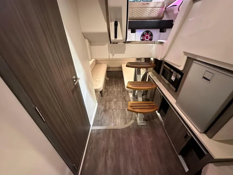 Slide: The Image of Interior of 2025 Sea Ray Sundancer 320, featuring modern wood flooring and compact kitchenette. - 21
