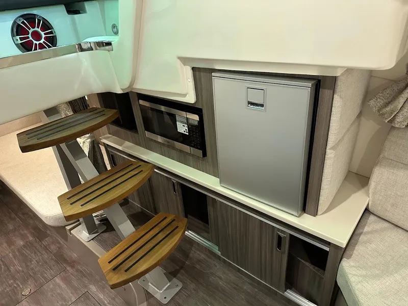 Slide: The Image of 2025 Sea Ray Sundancer 320 interior with modern seating and compact refrigerator. - 22