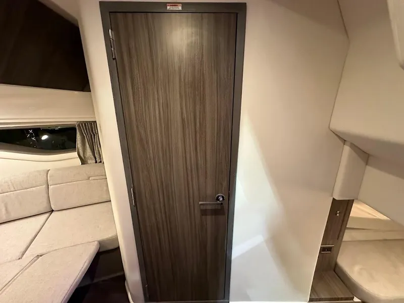 Slide: The Image of Interior of 2025 Sea Ray Sundancer 320, featuring a wooden door and beige seating area. - 26
