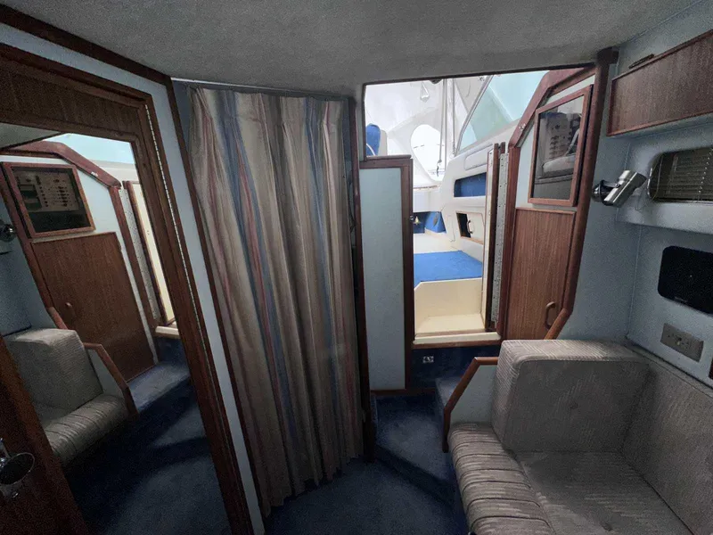 Slide: The Image of Interior of 1987 Sea Ray 270 Sundancer boat, featuring cozy seating and wood paneling. - 16