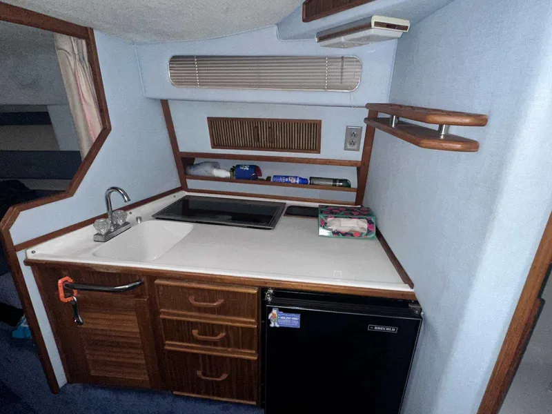 Slide: The Image of 1987 Sea Ray 270 Sundancer cabin kitchen with sink, stove, and mini fridge. - 19