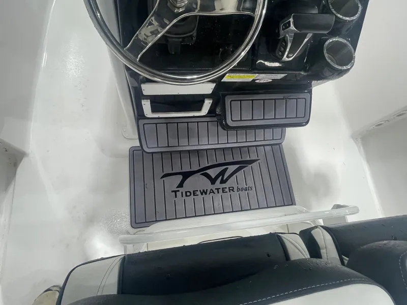 Slide: The Image of 2023 Tidewater 232cc boat interior with steering wheel and branded floor mat. - 15