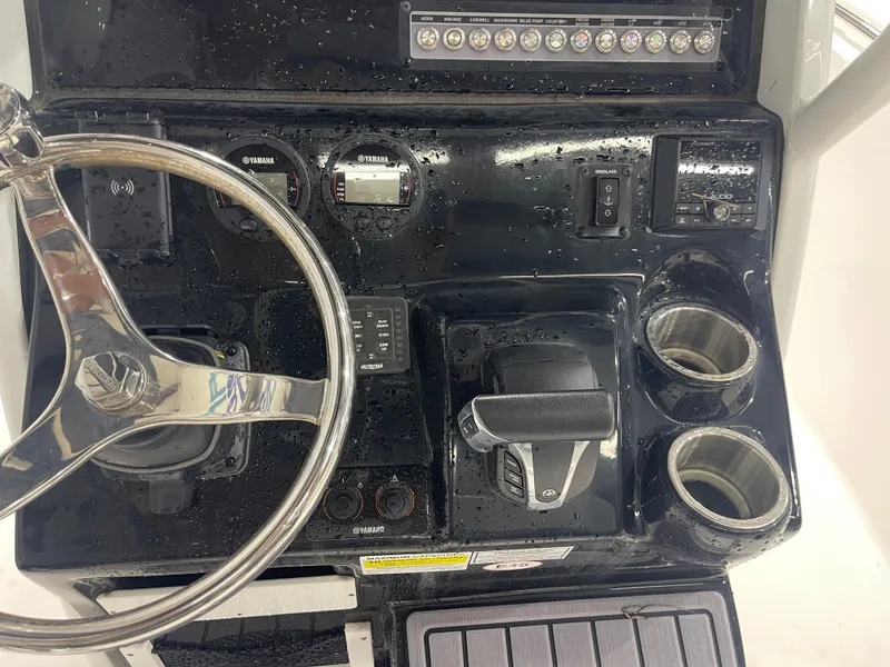 Slide: The Image of 2023 Tidewater 232cc boat dashboard with steering wheel, controls, and cup holders. - 16