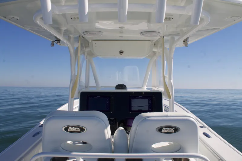 Slide: The Image of 2014 Yellowfin 32 Offshore boat interior with dual helm seats and navigation screens on open water. - 23