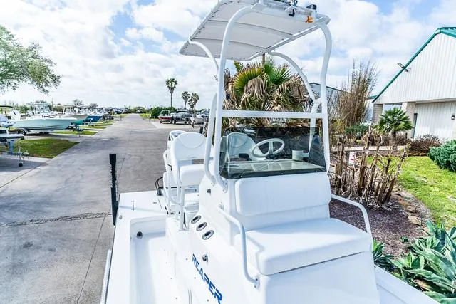 Slide: The Image of 2025 Majek 24 Reaper boat with white seating, parked outdoors on a sunny day. - 14