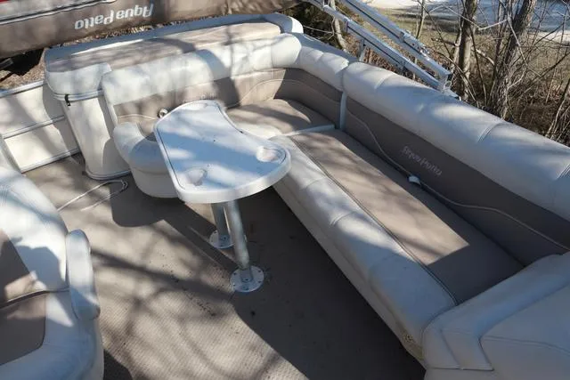 Slide: The Image of 2005 Godfrey Aqua Patio 220 RE boat interior with beige seating and table. - 5