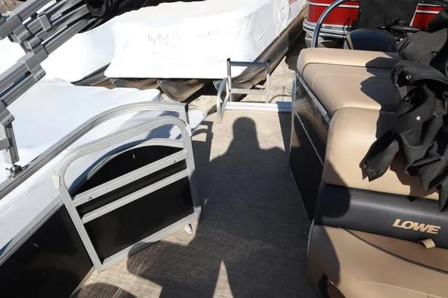 Slide: The Image of 2020 Lowe SS 210 V pontoon boat interior with beige seating and shadow on deck. - 7