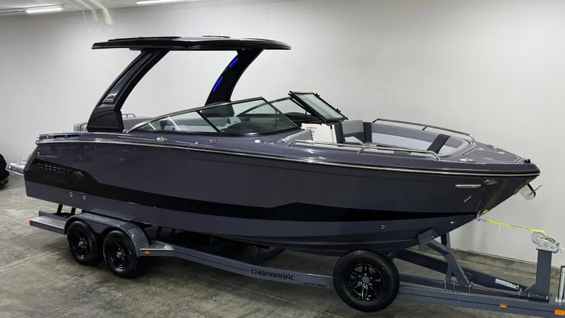 Slide: The Image of 2025 Chaparral 2870 SSX boat on trailer, sleek design, dark color, indoor setting. - 2