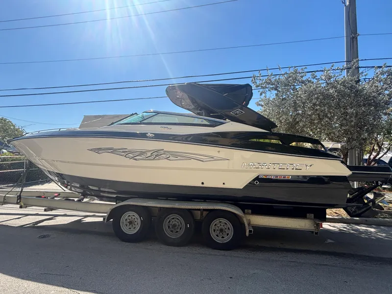 Slide: The Image of 2014 Monterey 328 Super Sport boat on trailer, parked outdoors under clear sky. - 0