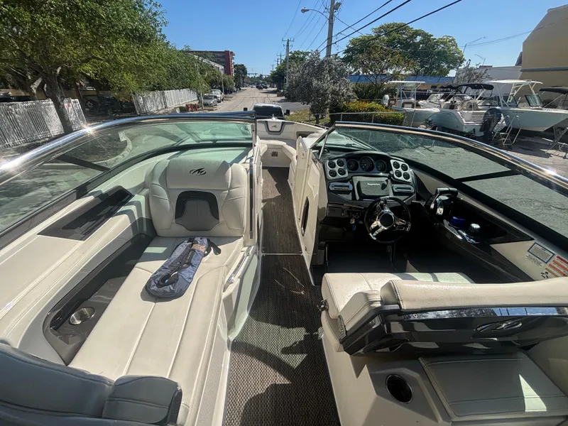 Slide: The Image of 2014 Monterey 328 Super Sport boat interior with seating and dashboard, parked outdoors. - 13