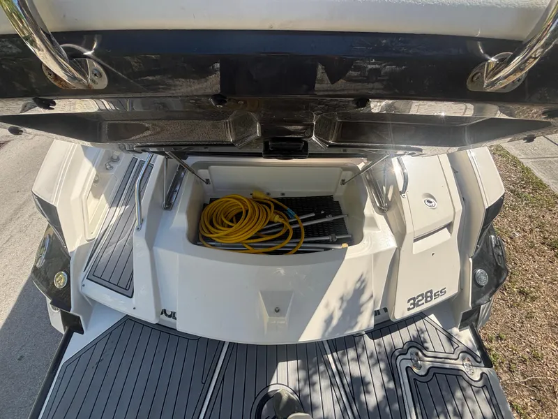 Slide: The Image of 2014 Monterey 328 Super Sport boat stern with storage compartment and coiled yellow cable. - 9