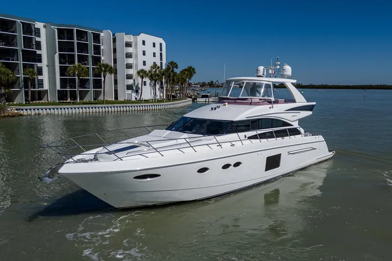 Slide: The Image of 2016 Princess Flybridge 64 Motor Yacht cruising near modern waterfront buildings. - 15