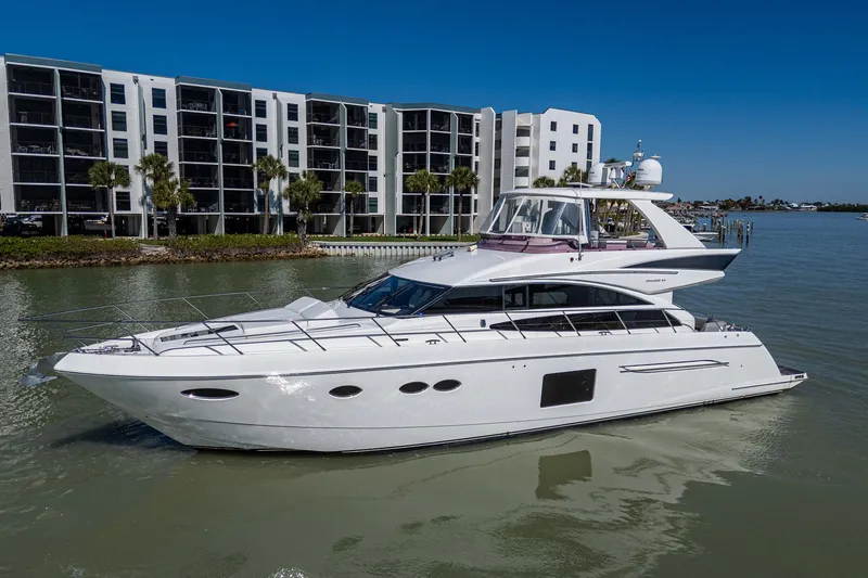 Slide: The Image of 2016 Princess Flybridge 64 Motor Yacht on calm water near modern buildings. - 16
