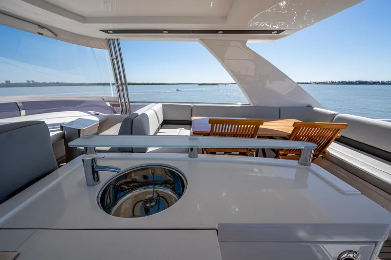 Slide: The Image of Luxurious 2016 Princess Flybridge 64 Motor Yacht with outdoor seating and sink, overlooking serene waters. - 39