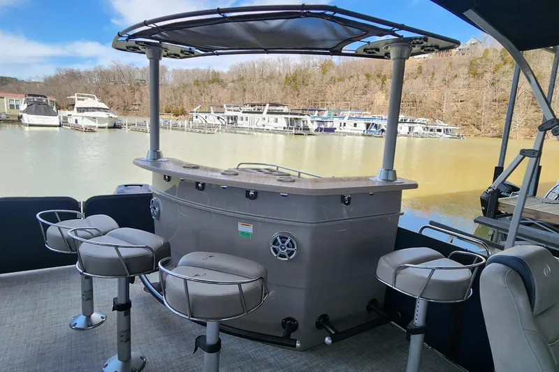 Slide: The Image of 2016 Premier 290 Grand Entertainer boat with bar and stools on a calm lake. - 9