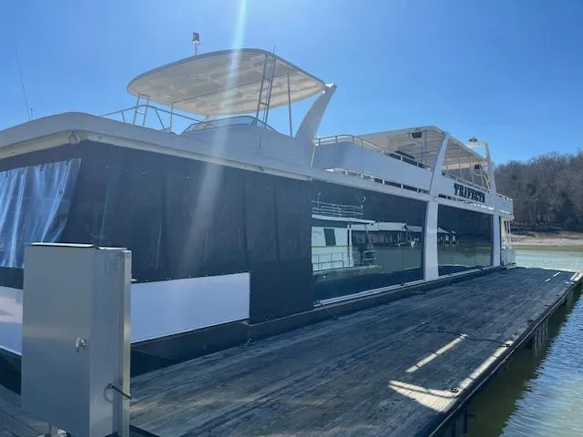 The Image of 2013 Thoroughbred houseboat docked on a sunny day, featuring a spacious upper deck. - 0