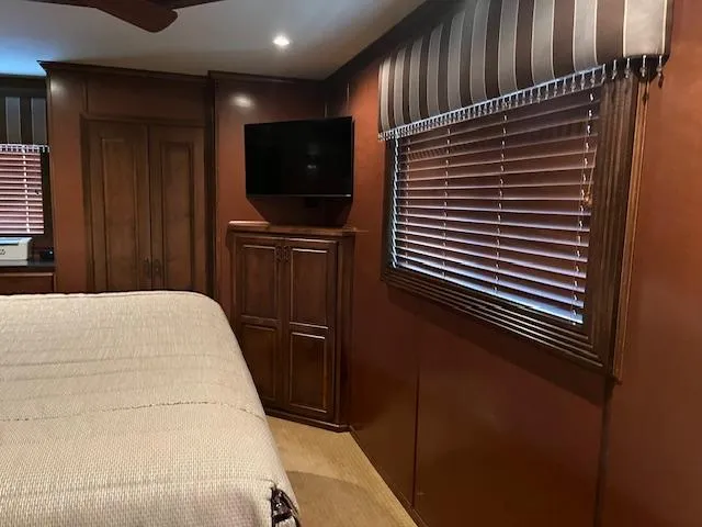 Slide: The Image of Interior of 2013 Thoroughbred houseboat with wood paneling, bed, TV, and window blinds. - 26