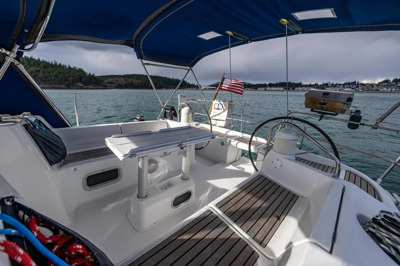 Slide: The Image of 2001 Jeanneau Sun Odyssey 40 sailboat cockpit with seating, table, and steering wheel on calm waters. - 27