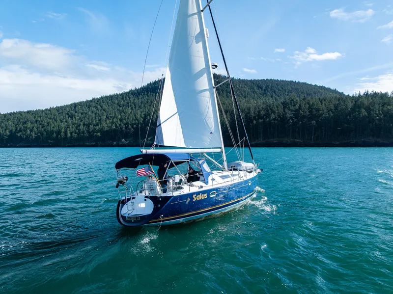 Slide: The Image of Jeanneau Sun Odyssey 40 sailboat cruising on blue water near forested shoreline, 2001 model. - 4