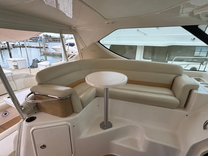 Slide: The Image of 2008 Tiara Yachts 3900 Sovran interior with curved seating and small table, docked at marina. - 9