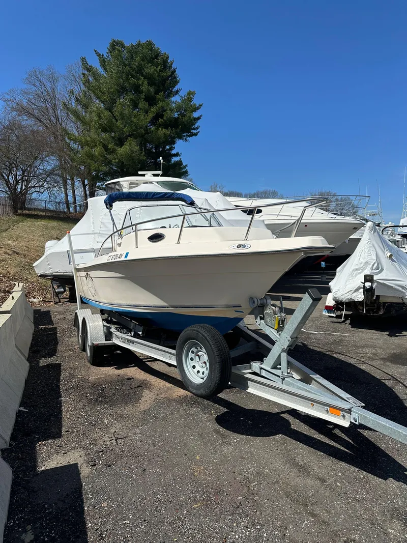 Slide: The Image of 1998 Key West 2020 Walkaround boat on trailer, parked outdoors under clear blue sky. - 2