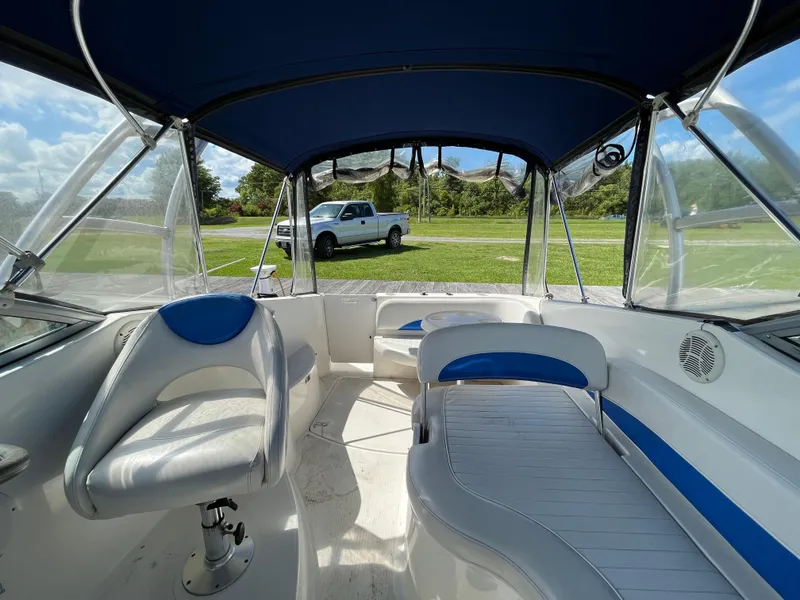 Slide: The Image of 2006 Bayliner 265 Cruiser interior with blue canopy, white seating, and parked truck outside. - 14