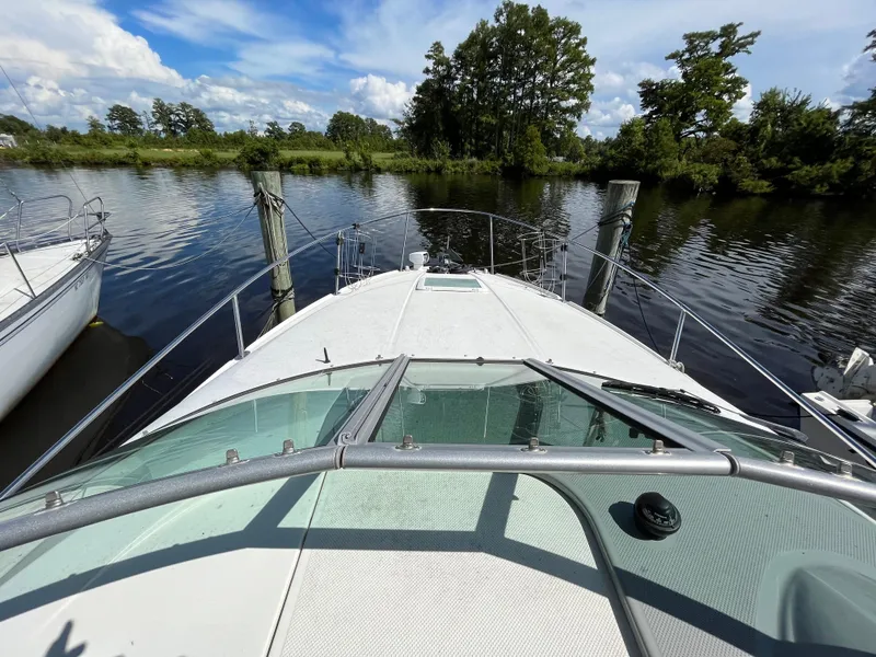Slide: The Image of 2006 Bayliner 265 Cruiser on calm water, surrounded by lush greenery and blue sky. - 15