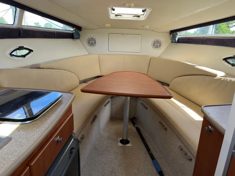 Slide: The Image of Interior of 2006 Bayliner 265 Cruiser with beige seating and wooden table. - 23