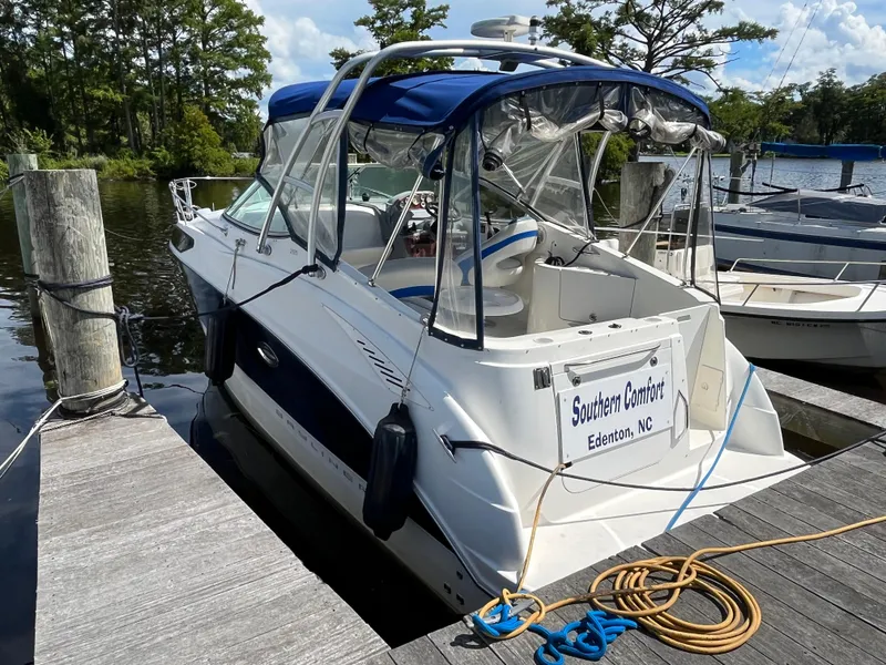 Slide: The Image of 2006 Bayliner 265 Cruiser docked, featuring blue canopy and white hull, in a serene marina setting. - 3
