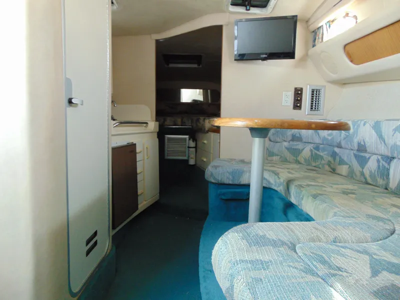 Slide: The Image of 1995 Sea Ray 290DA cabin interior with seating, table, and kitchenette. - 13