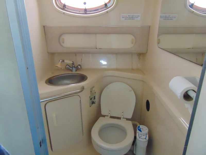 Slide: The Image of 1995 Sea Ray 290DA boat bathroom with sink, toilet, and porthole window. - 14