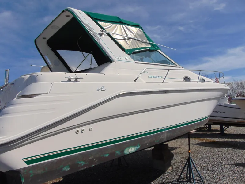 Slide: The Image of 1995 Sea Ray 290DA boat with green canopy, displayed on stands under a clear sky. - 2