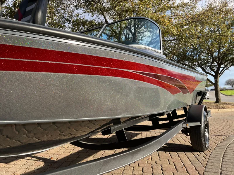 Slide: The Image of 2021 Ranger VS1782 WT boat with red stripe, parked on a brick driveway. - 20