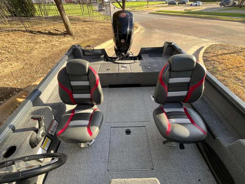 Slide: The Image of 2021 Ranger VS1782 WT boat interior with two seats and motor, parked on a sunny day. - 49