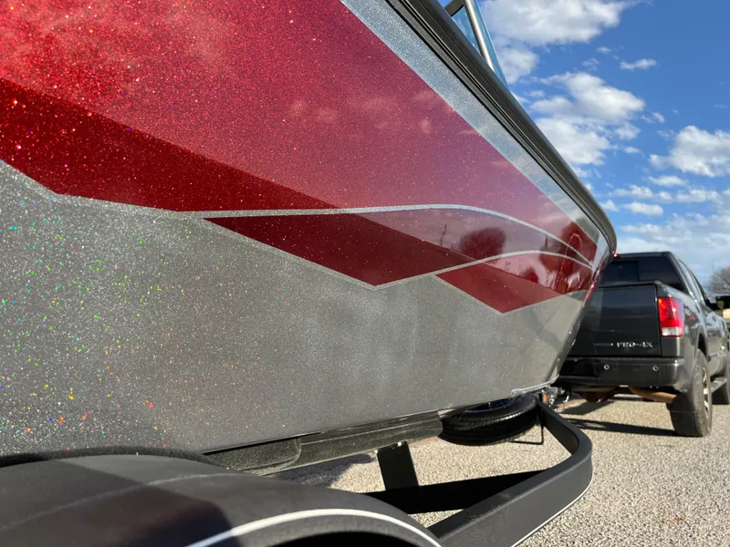 Slide: The Image of 2021 Ranger VS1782 WT boat with red and silver design, parked on a sunny day. - 51
