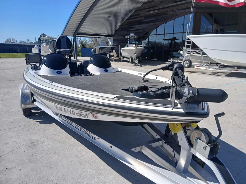 Slide: The Image of 2006 Skeeter 21 boat on trailer, parked outdoors near a modern building. - 12