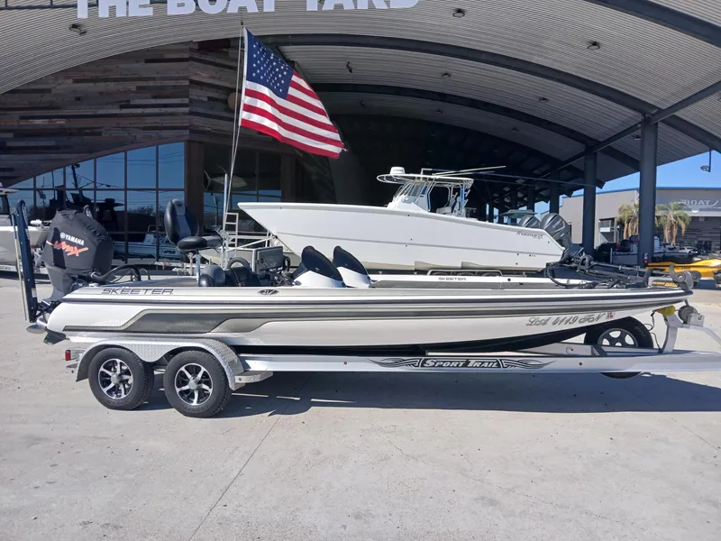 Slide: The Image of 2006 Skeeter 21 boat with American flag, parked at a boat yard. - 18