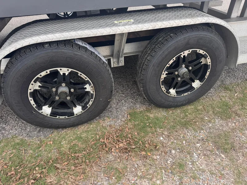 Slide: The Image of Trailer wheels of a 2019 Catalyst 260 Catamaran on gravel and grass. - 13
