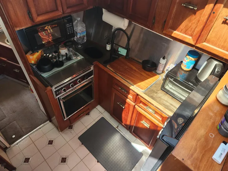 Slide: The Image of 1977 Pacemaker 40 Sportfisherman kitchen with wooden cabinets, stove, and countertop appliances. - 13