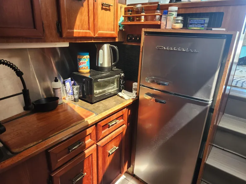 Slide: The Image of 1977 Pacemaker 40 Sportfisherman kitchen with wooden cabinets, stainless steel fridge, and appliances. - 15