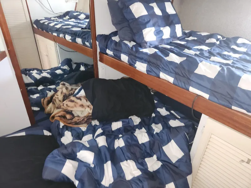 Slide: The Image of Bunk beds with blue checkered bedding in a 1977 Pacemaker 40 Sportfisherman cabin. - 17