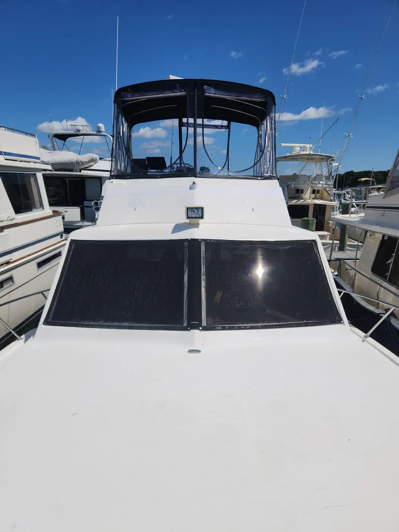 Slide: The Image of 1977 Pacemaker 40 Sportfisherman boat docked, featuring a sleek white exterior and spacious deck. - 27