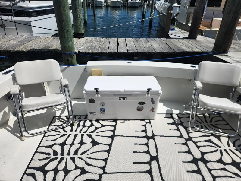 Slide: The Image of 1977 Pacemaker 40 Sportfisherman boat deck with chairs, cooler, and patterned rug at marina. - 4
