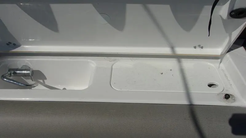 Slide: The Image of 2025 Sportsman Open 302 boat storage compartment with latch and drainage. - 9