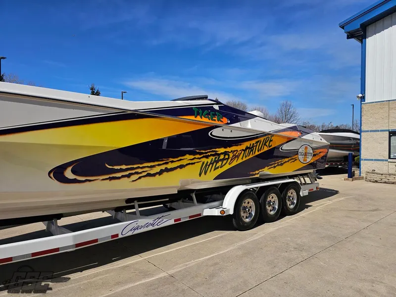 Slide: The Image of 2003 Cigarette 42 Tiger speedboat with vibrant graphics on a trailer, parked outdoors. - 18