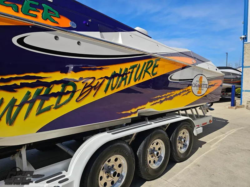 Slide: The Image of 2003 Cigarette 42 Tiger boat with vibrant graphics on a trailer. - 24