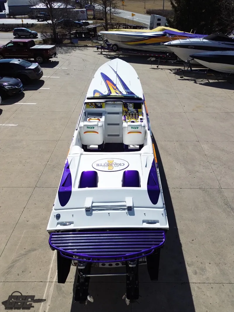 Slide: The Image of 2003 Cigarette 42 Tiger speedboat with vibrant purple and white design, parked on concrete. - 43